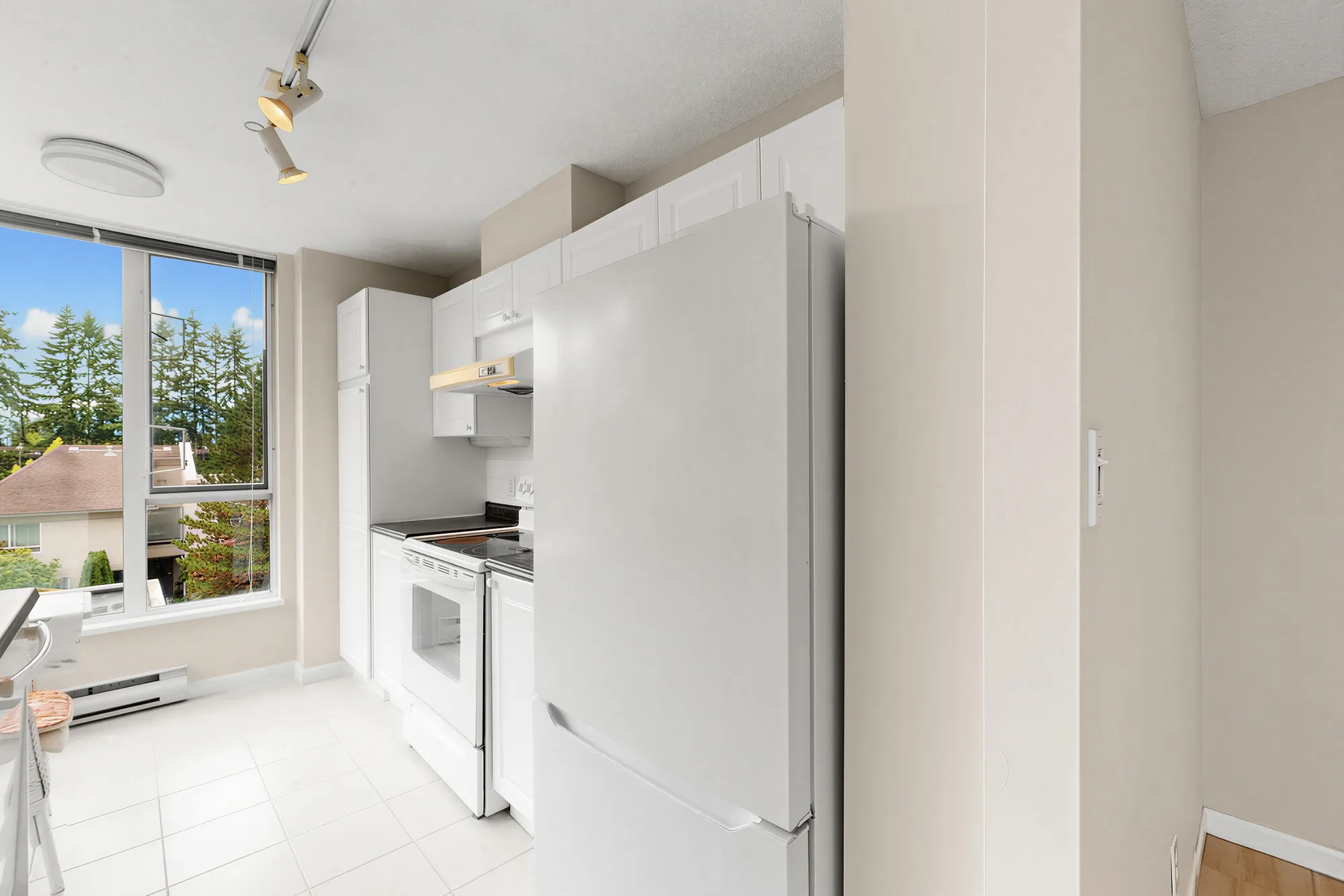 The counter running to the corner window, fridge on the left