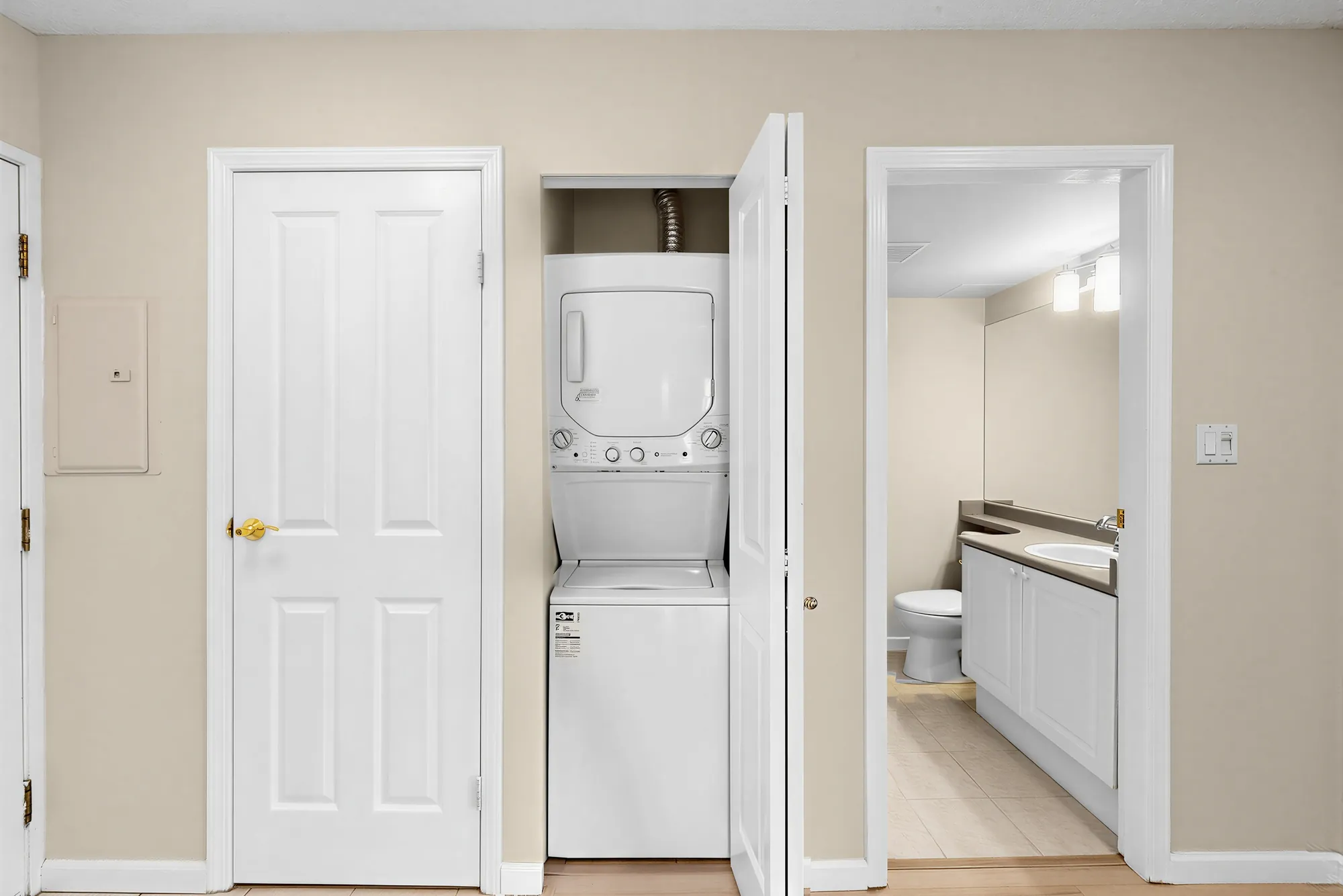 A stacked washer and dryer in a cupboard off the hall
