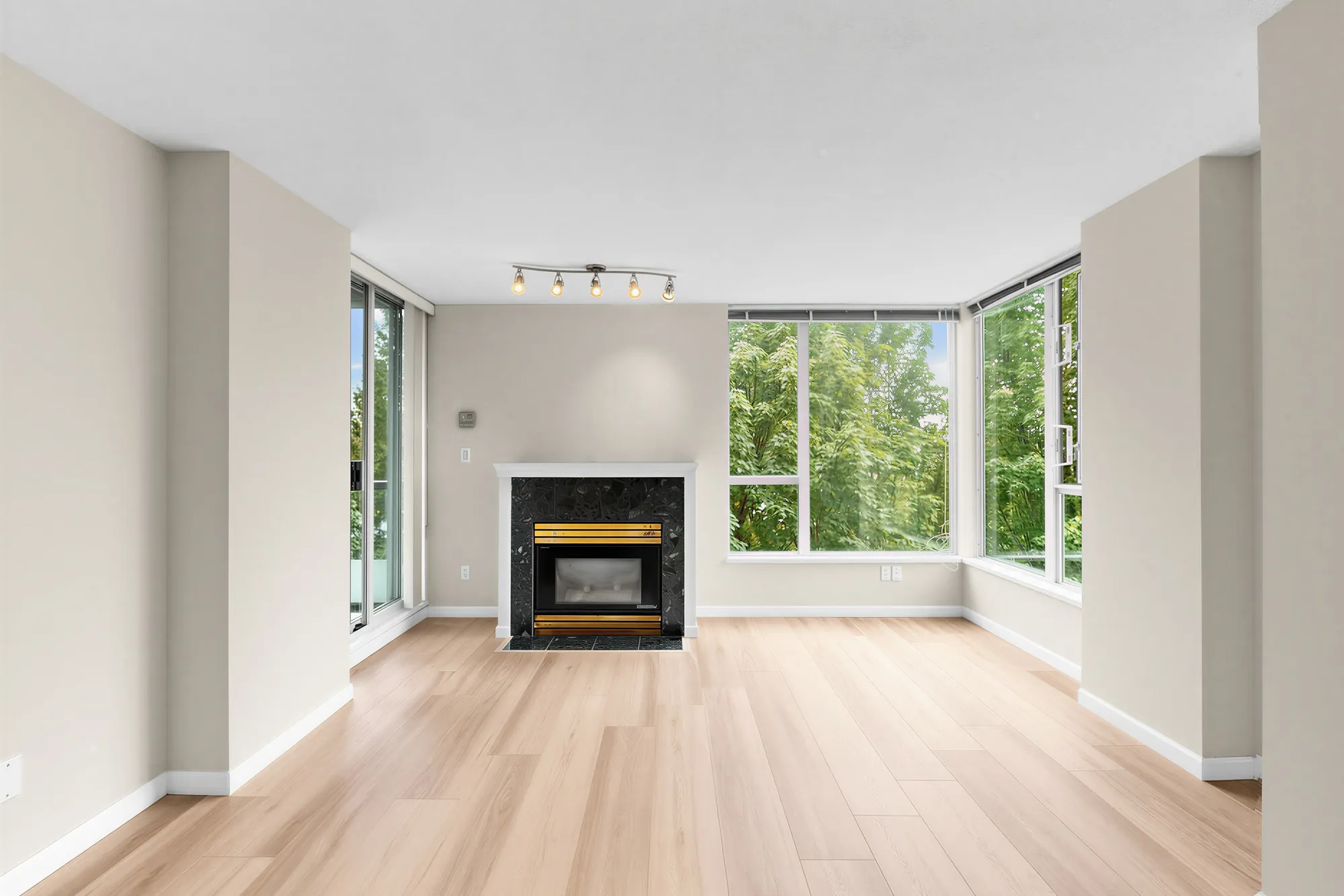 The fireplace wall with windows either side, trees beyond the glass