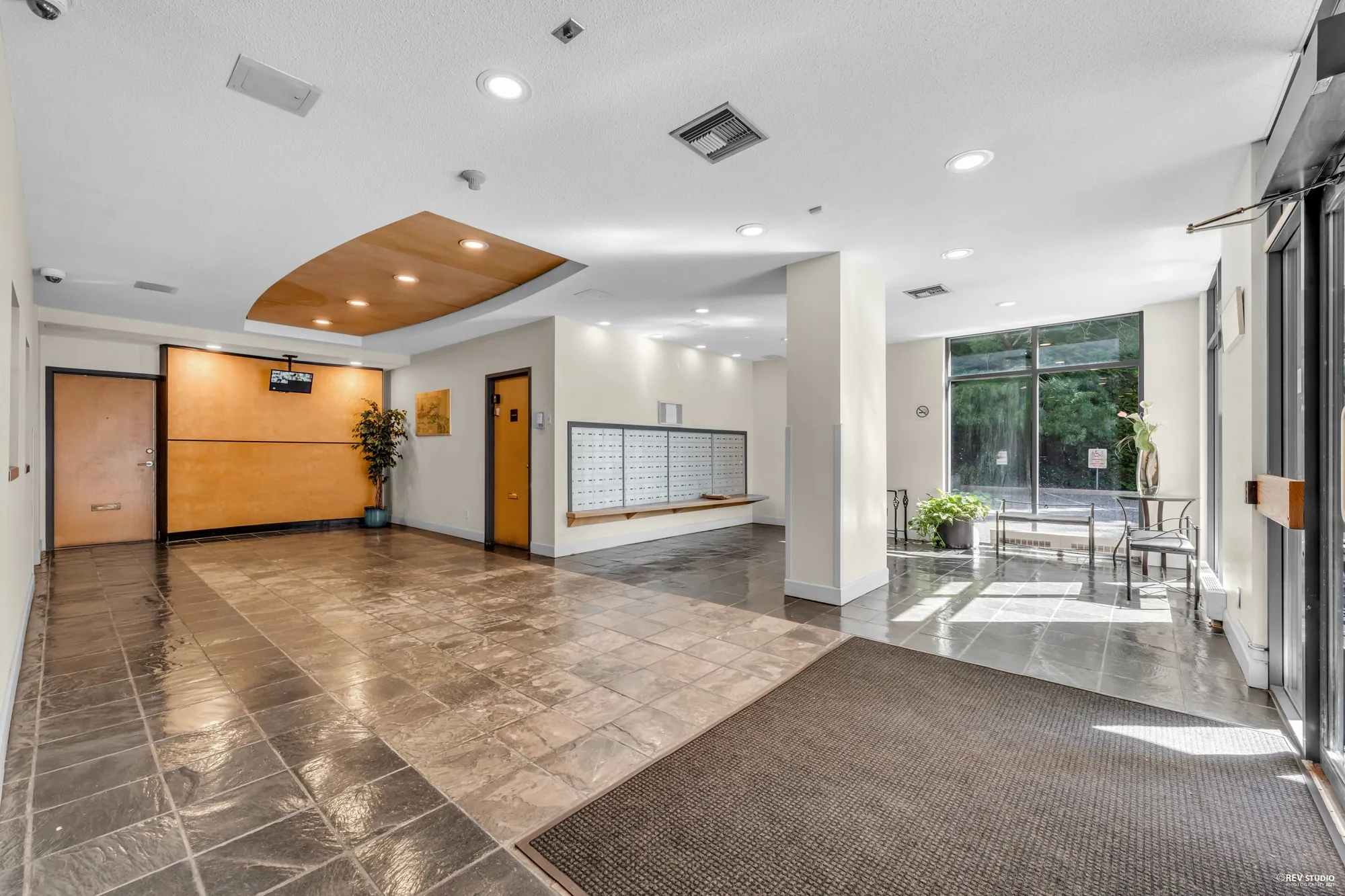 The lobby with a tiled floor, mailboxes along the wall and glass to the garden