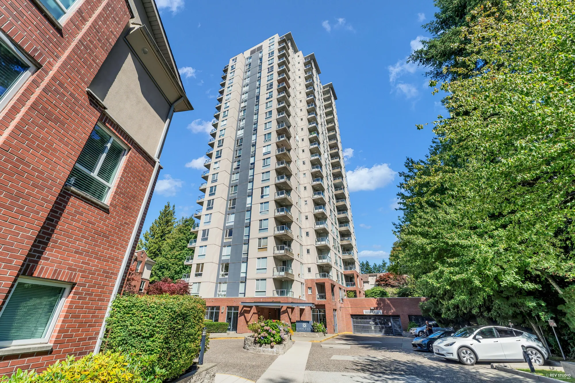 The tower at 7077 Beresford Street seen from the driveway, brick base and trees